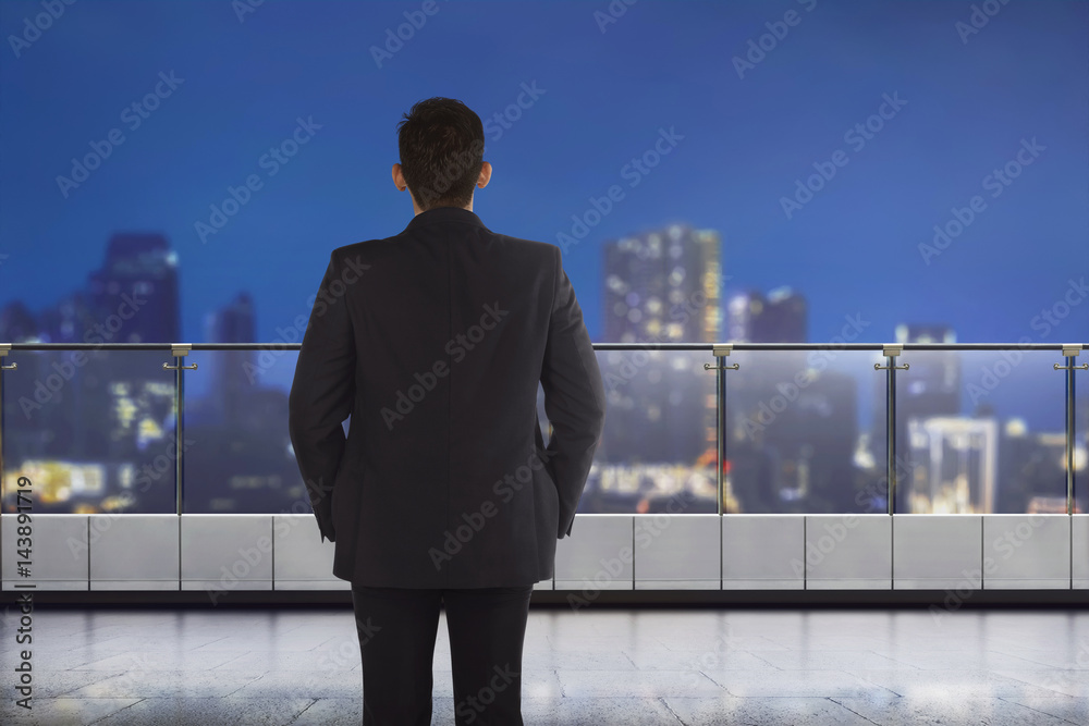 Back view of asian businessman looking at the city through window