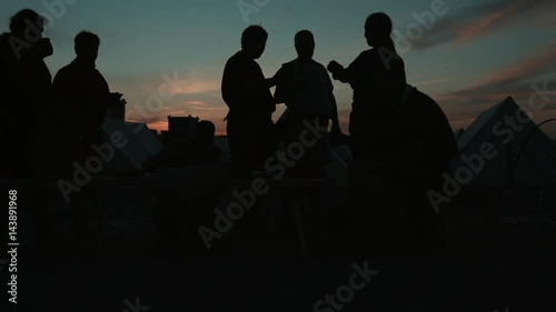 Silhouettes of medieval people who eating at sunset
