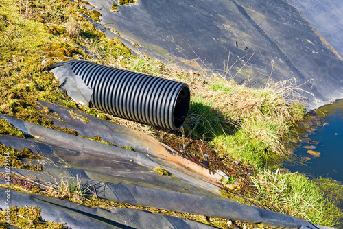 Landfill leachate pouring into pond from a black pipe. Location Ronneby, Sweden. photo