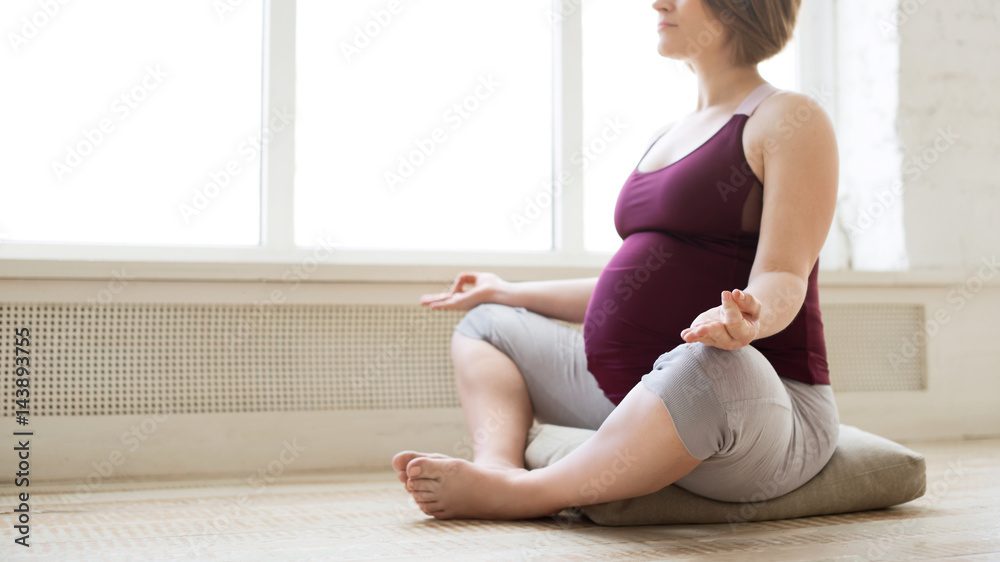 Pregnant woman meditation in lotus pose at home while doing yoga Pregnant woman meditation in lotus pose at home while doing yoga