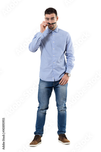 Cool macho smart casual man taking off sunglasses staring at camera. Full body length portrait isolated over white background.