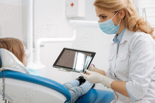 Lovely modern dentist using a tablet for illustration