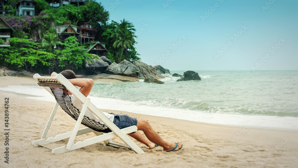 Young man relax in beach chair and enjoy seascape on tropical beach Stock  Photo | Adobe Stock