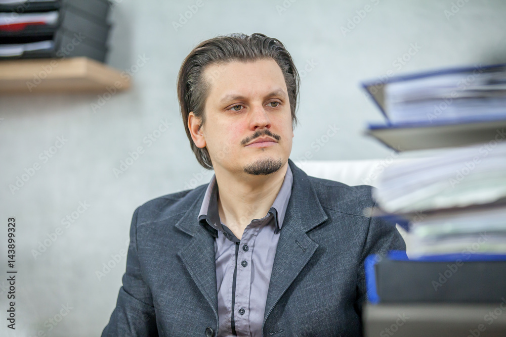 Obraz premium A young businessman is looking at the blue folders on his table.