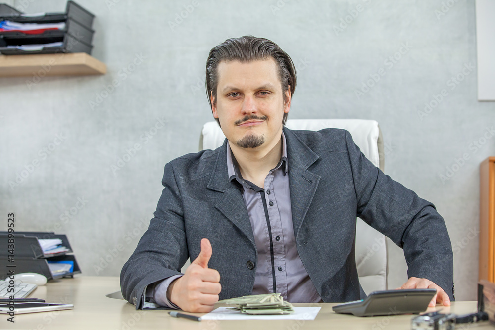 A businessman sitting in his chair is giving a thumbs up. A businessman sitting in his chair is giving a thumbs up.