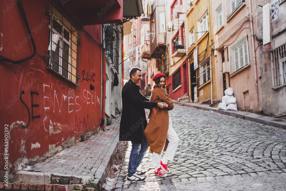 European couple walking at old Istanbul streets. Casual style, red beret and beige coat