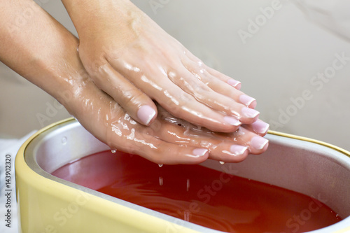 Photo Process paraffin treatment of female hands in beauty salon