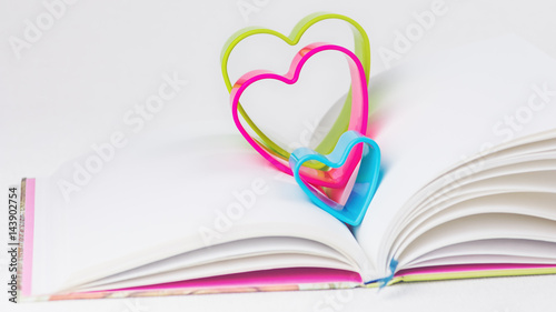 Red blue and green hearts over diary book on white table