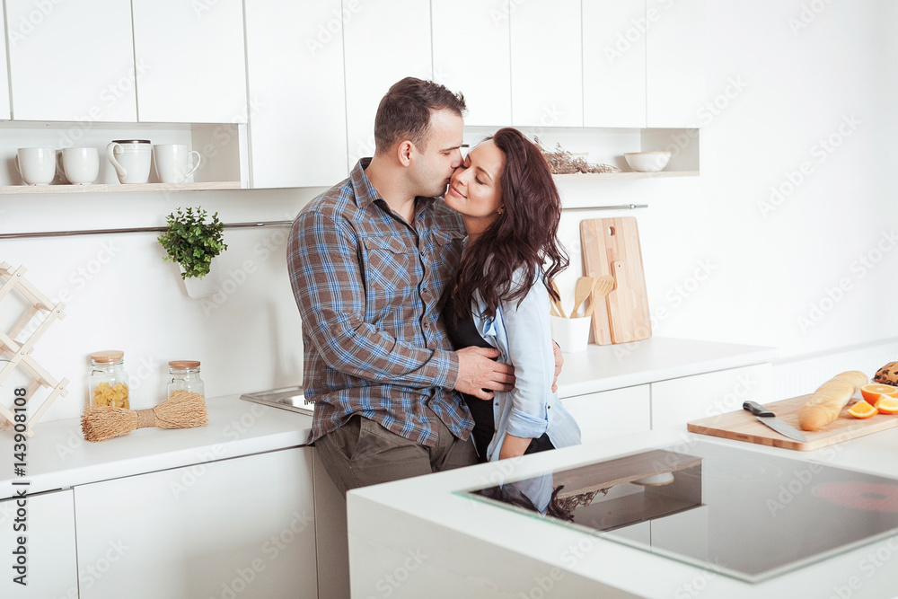 Happy couple hugging in the white loft stile kitchen Happy couple hugging in the white loft stile kitchen
