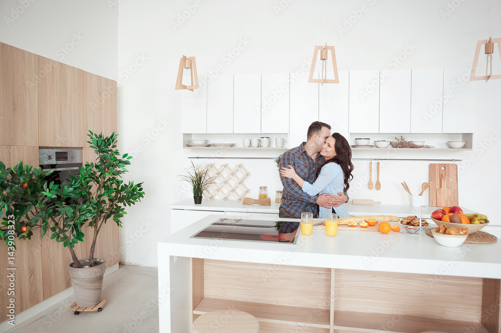 Happy couple hugging in the white loft stile kitchen