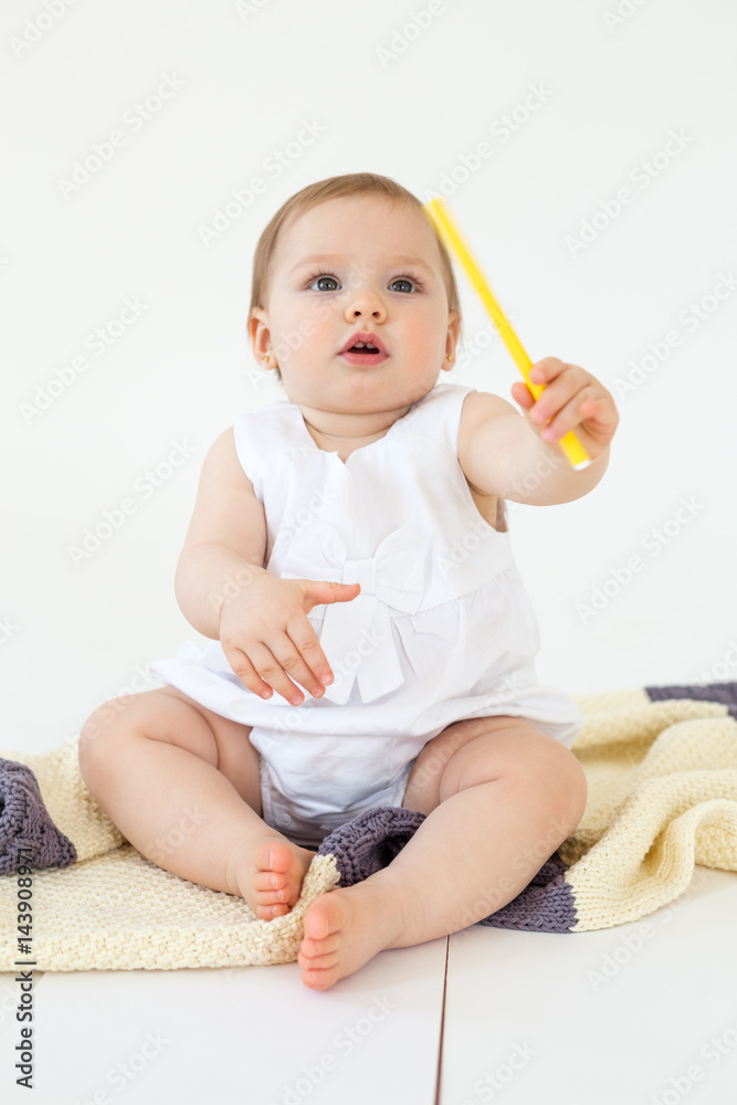Pretty little girl sitting on floor on plaid holding markers Pretty little girl sitting on floor on plaid holding markers