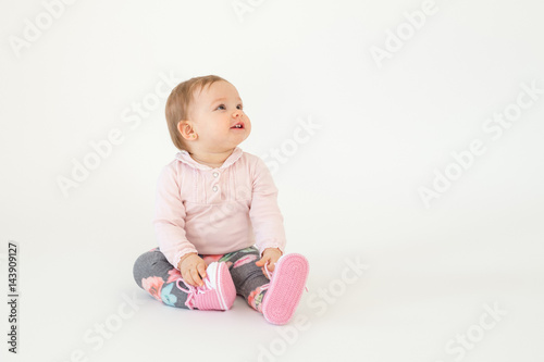 Cute little baby girl sitting on floor isolated