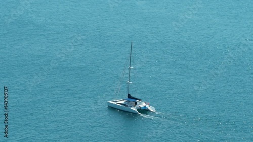 A catamaran (Hobie Cat) sailboat (twin hulls) is sailing on a beautiful open ocean.  photo
