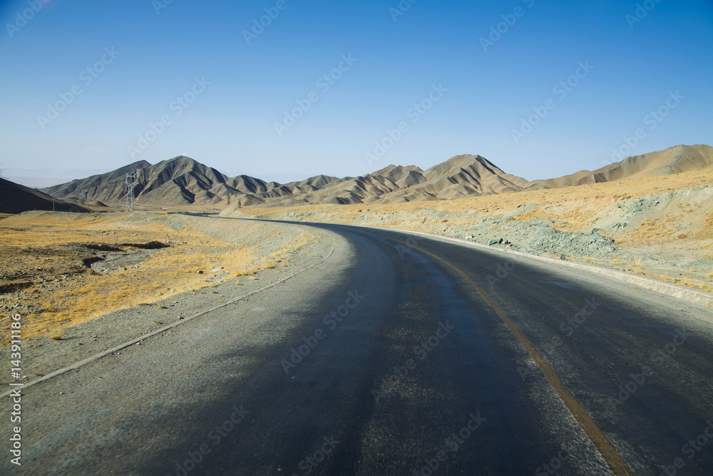 Long empty curve asphalt road in desert with  clear blue sky .