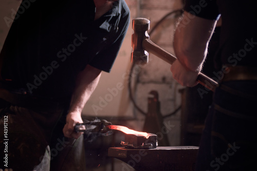 Farriers forging horseshoe on anvil