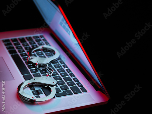 Network security, set of handcuffs sitting on laptop computer photo