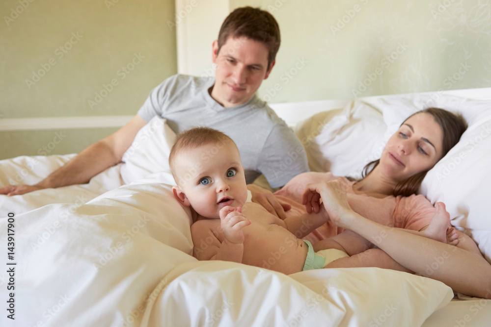 Portrait of baby girl lying on bed with parents Portrait of baby girl lying on bed with parents
