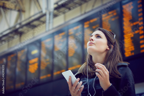 Woman looking at departure information, London, UK