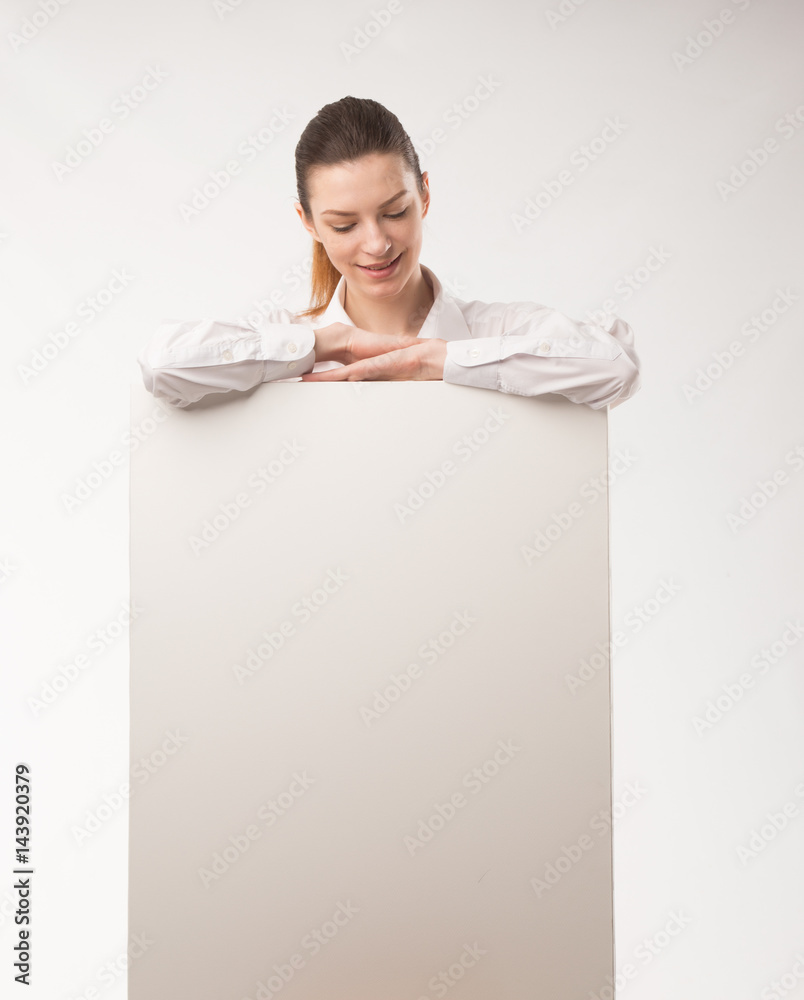 Young happy woman showing presentation, pointing on placard over gray background Young happy woman showing presentation, pointing on placard over gray background