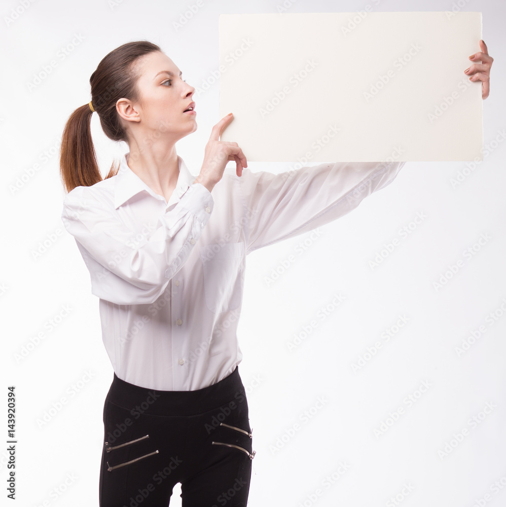Young happy woman showing presentation, pointing on placard over gray background Young happy woman showing presentation, pointing on placard over gray background