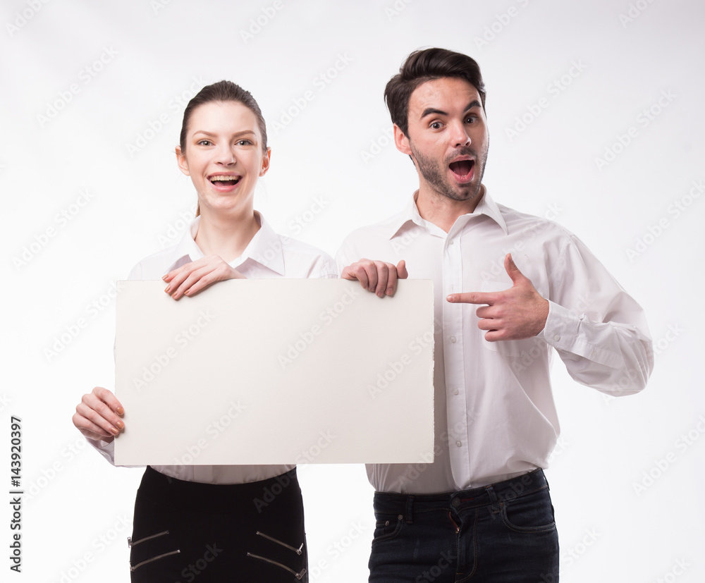 Young happy couple showing presentation pointing on placard over gray background Young happy couple showing presentation pointing on placard over gray background