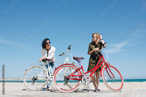 Two friends on the beach with bicycles