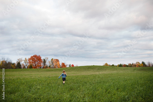 Young girl running in open field, Lakefield, Ontario, Canada photo