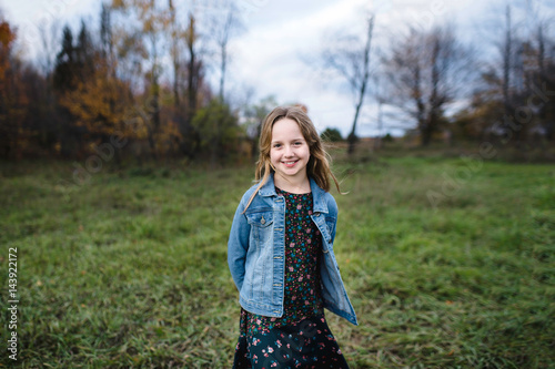 Young girl smiling in field in denim jacket, Lakefield, Ontario, Canada photo