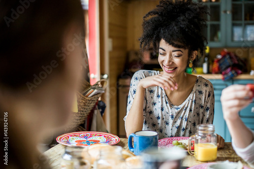 Three friends sitting around table, eating breakfast