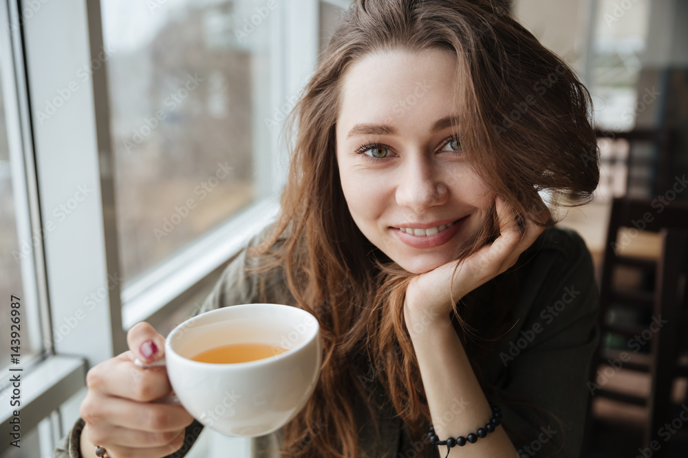 Cute happy young beautiful lady sitting in cafe drinking tea Cute happy young beautiful lady sitting in cafe drinking tea