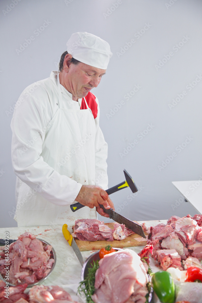 Lots of meat is on a table in front of the chef who is preparing dinner for the guests.