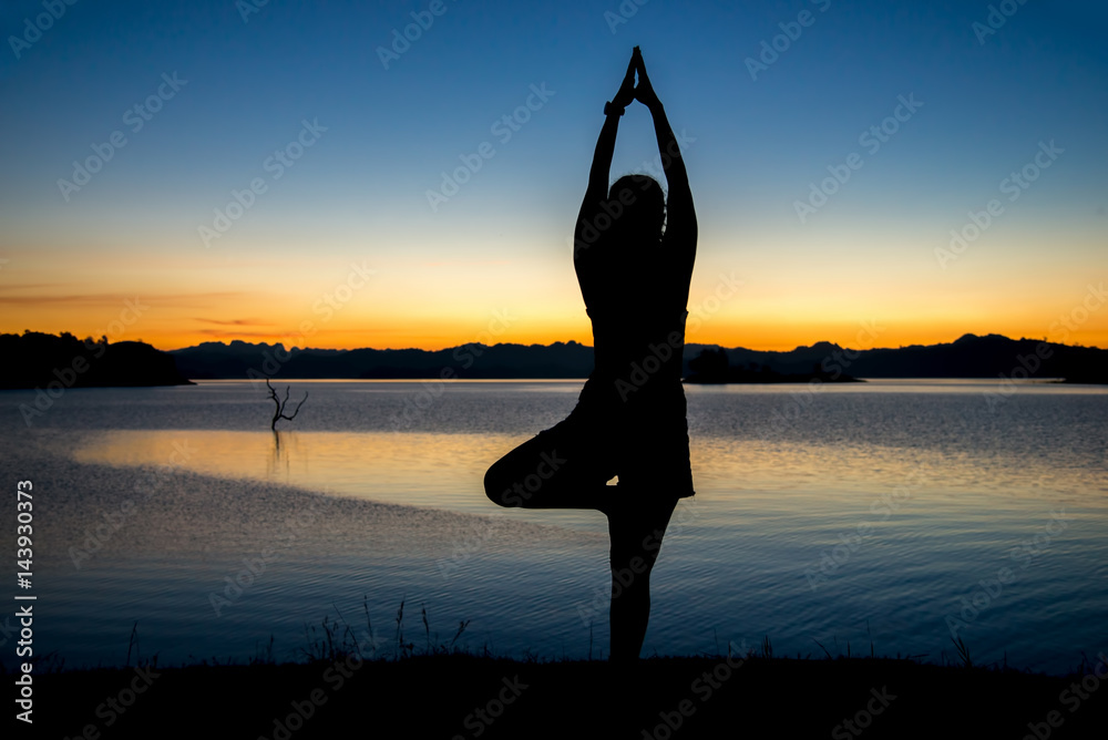 Silhouette a woman playing yoga on twilight. Sunset sky background