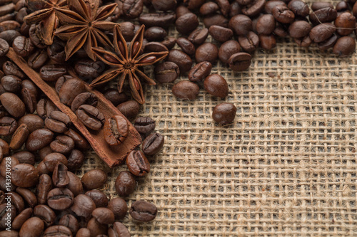 Coffee beans and illicium on a background of burlap. Roasted coffee beans background close up. Coffee beans pile from top with copy space for text. Seasoning. Spice. Badian. Coffee house.
