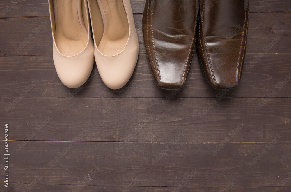 High heels and leather shoes are on wooden background
