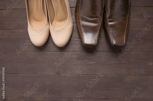 High heels and leather shoes are on wooden background