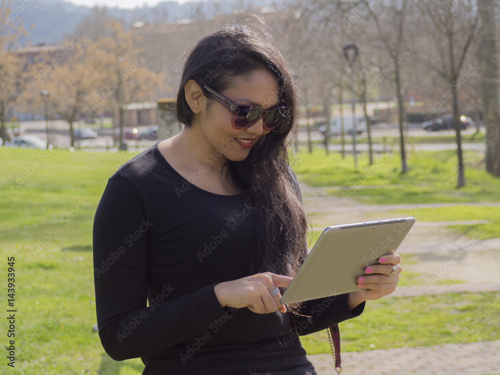 Fototapeta premium Retrato de mujer trabajando desde su tablet en la paz de la naturaleza, primer plano.