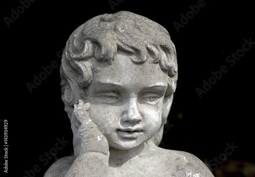 Vintage stone garden statue of young girl with hand on cheek, thoughtful beautiful expression