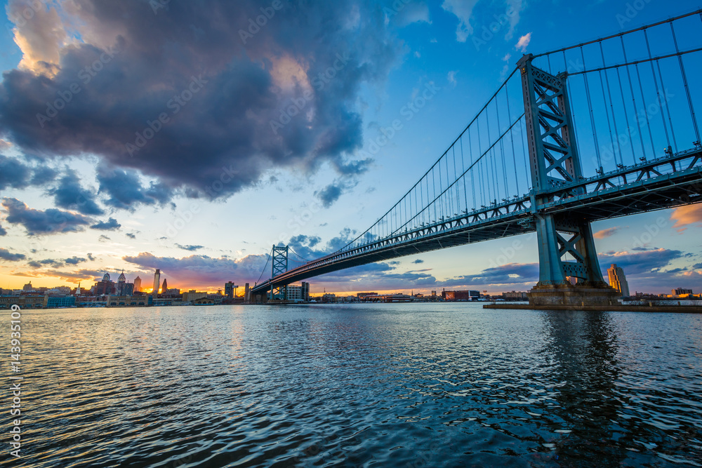 Fototapeta premium The Benjamin Franklin Bridge and and Delaware River at sunset, seen from Camden, New Jersey.