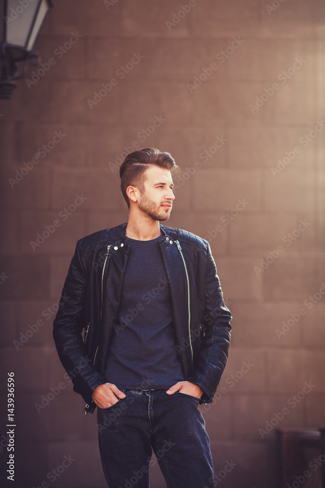 fashionable young man in a leather jacket posing in the street fashionable young man in a leather jacket posing in the street