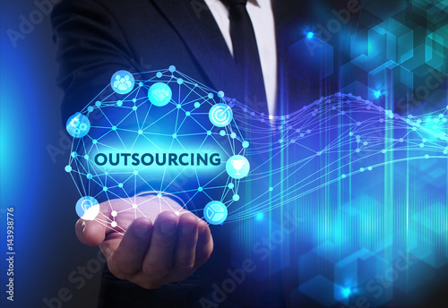 Business, Technology, Internet and network concept. Young businessman working on a virtual screen of the future and sees the inscription: Outsourcing