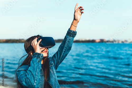 Young girl in virtual reality glasses in the park