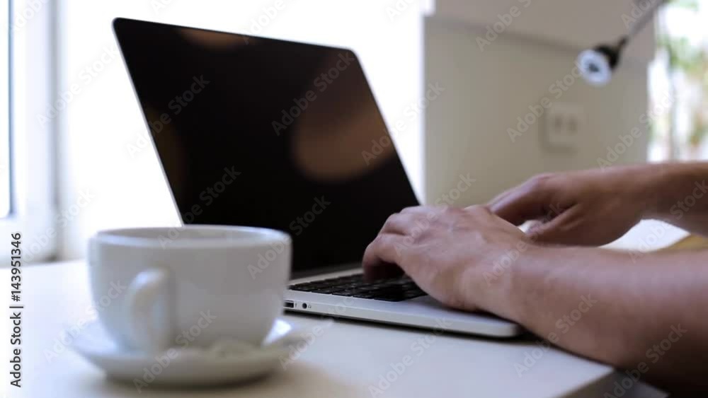 Man working with a laptop in the office and drinking coffee Man working with a laptop in the office and drinking coffee