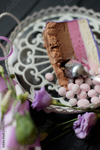 Piece of blueberry pie take with spoone near flowers on black wooden background photo