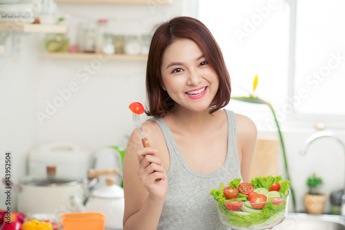 Beautiful young asian girl eating salad. smiling happy girl eating healthy food.