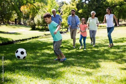 Multi generation family playing football in park