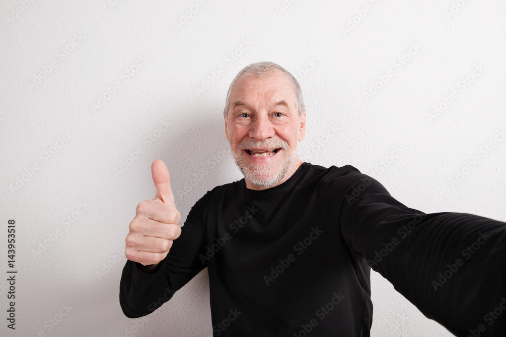 Senior man in black woolen sweater, thumb up, studio shot. Senior man in black woolen sweater, thumb up, studio shot.