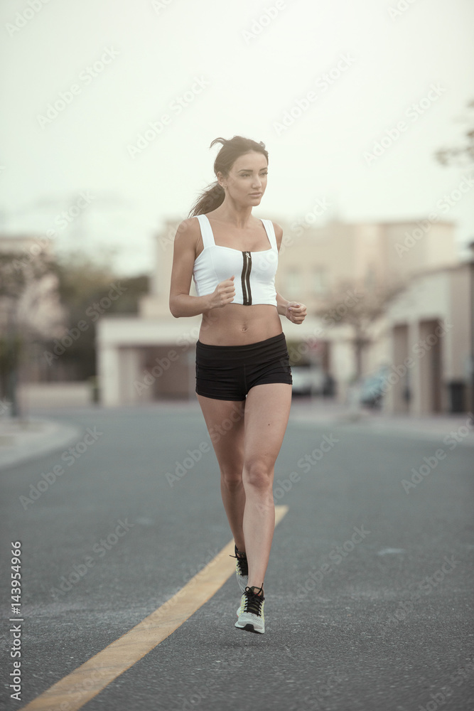 Tall athletic fitness model running in a suburban area showing