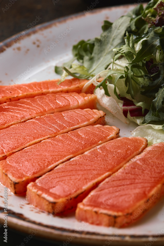 Fried slices of salmon with lettuce and sauce