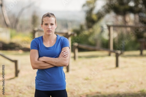 Fit woman standing with arms crossed in boot camp