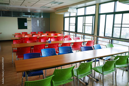 many color chairs with wood table in cafeteria.